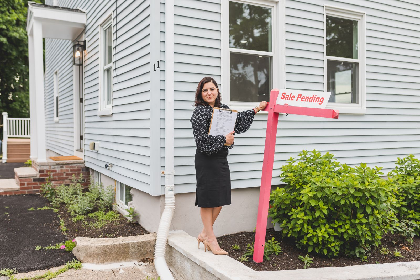 Real estate agent standing outside a home with property documents